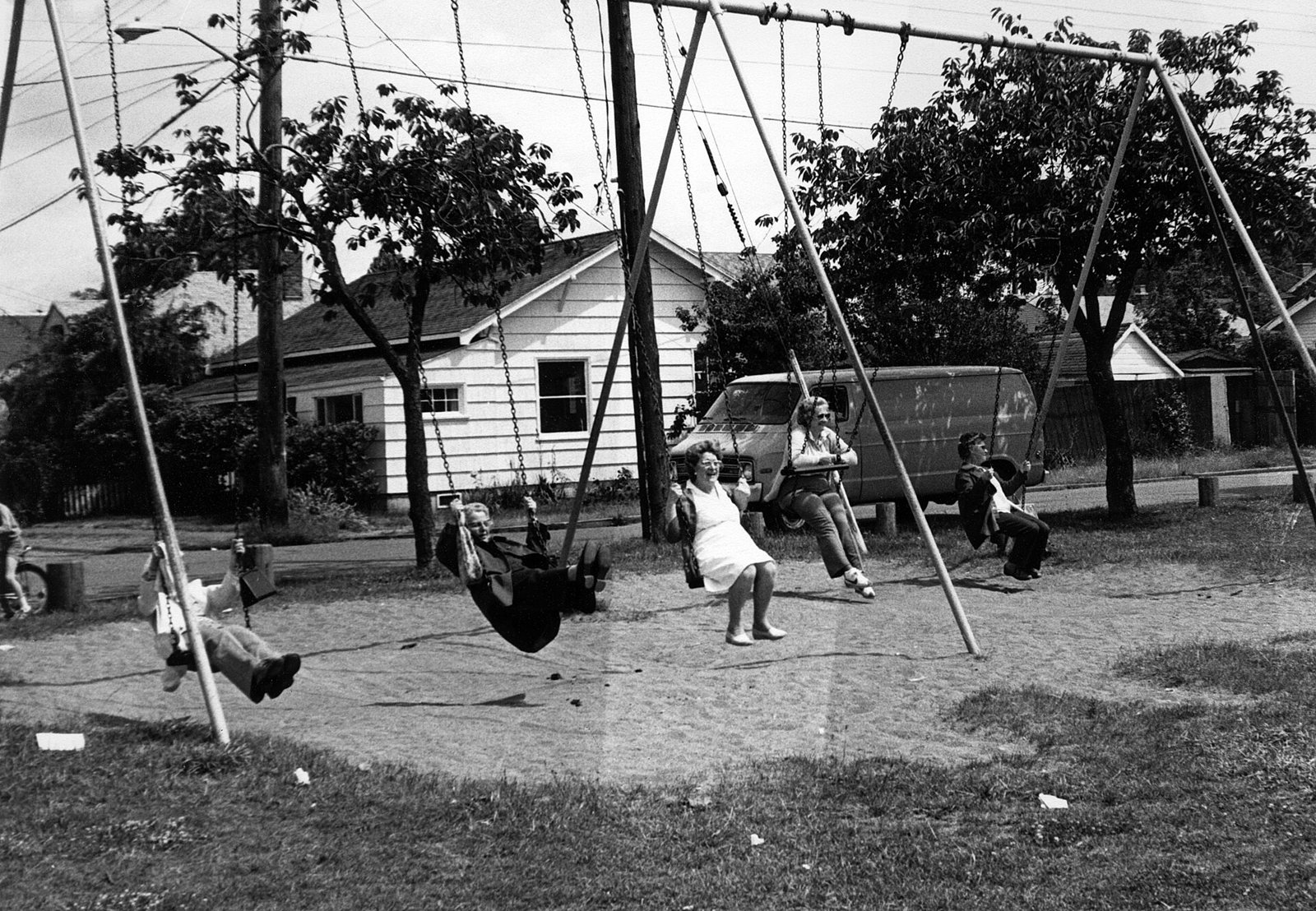 Cinco mujeres mayores columpiándose en un parque infantil, en blanco y negro